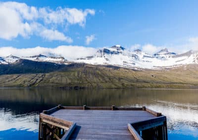 A pier, the sea, snowy mountains and blue sky of the Eastfjords