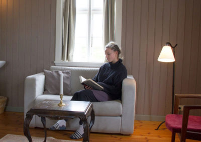A young lady sitting in a sofa and reading, in the hotel Flatey suite