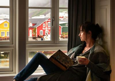 Young lady in a window seat looking out to harbour and colorful houses