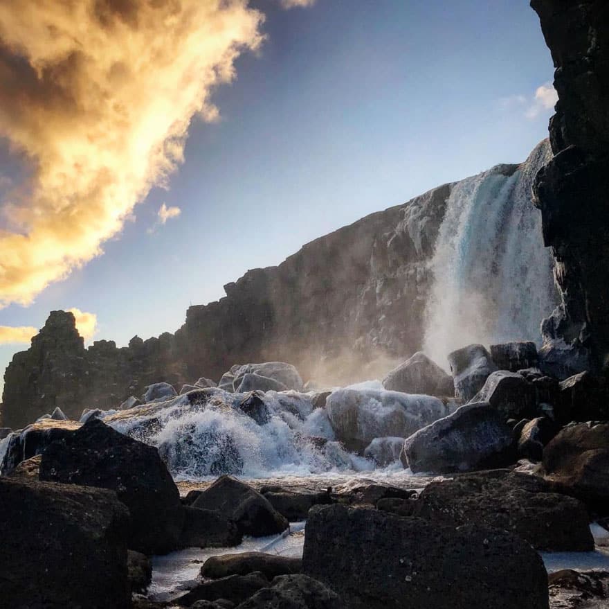 A waterfall with frozen rocks and dramatic dusk skies